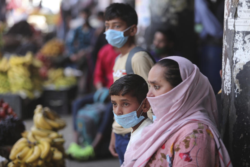 Passengers wearing masks as a precaution against the coronavirus wait for transportation at a bus station in Jammu, India, Friday, March 26, 2021.(AP Photo/Channi Anand)