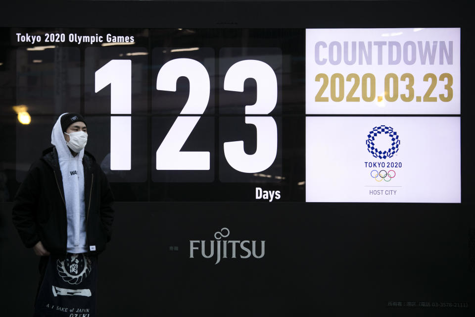 A man stands in front of a countdown display for the Tokyo 2020 Olympics and Paralympics in Tokyo, Monday, March 23, 2020. Japanese Prime Minister Shinzo Abe acknowledged that a postponement of the crown jewel of the sporting world could be unavoidable. Canada and Australia then added to the immense pressure that has been steadily mounting on organizers by suggesting that they wouldn't send athletes to Tokyo this summer. (AP Photo/Jae C. Hong)