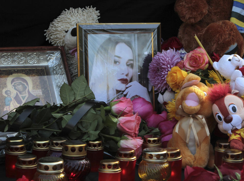 Candles, flowers, icons, and toys are placed by victims' photographs during a ceremony commemorating an attack on a vocational college, in Kerch, Crimea, Thursday, Oct. 18, 2018. Authorities on the Crimean Peninsula were searching for a possible accomplice of the student who carried out a shooting and bomb attack on a vocational school, killing 20 people and wounding more than 50 others, an official said Thursday. (AP Photo/Str)