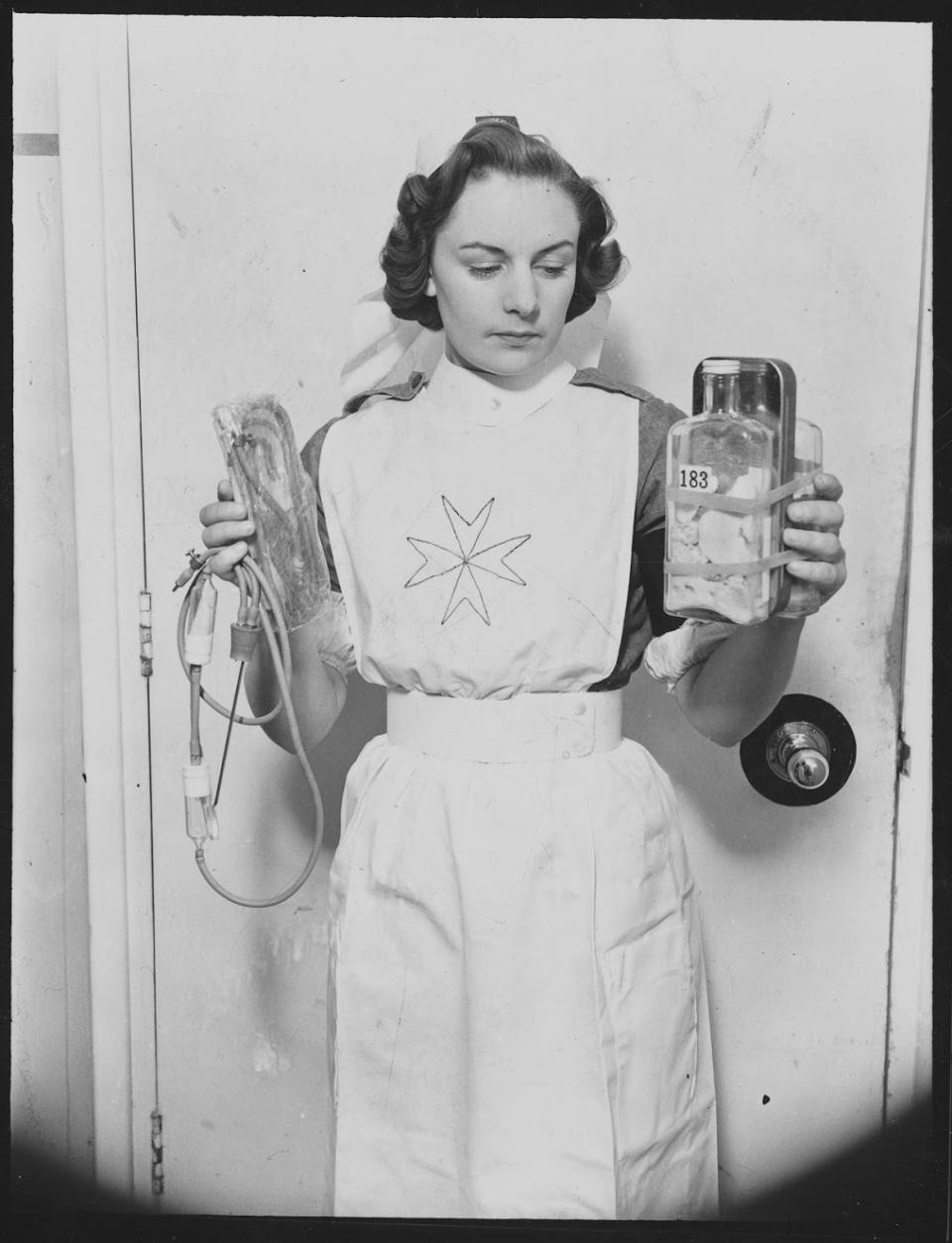 A nurse holding equipment for the transfusion of dried plasma, at the Army Blood Supply Depot in Southmead Hospital, Bristol