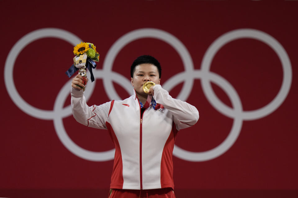 Wang Zhouyu of China celebrates on the podium after receiving the gold medal in the women's 87kg weightlifting event at the 2020 Summer Olympics, Monday, Aug. 2, 2021, in Tokyo, Japan. (AP Photo/Luca Bruno)