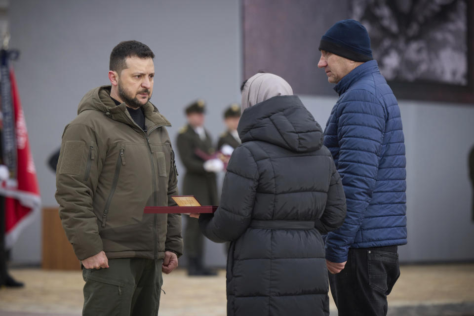 Ukrainian President Volodymyr Zelenskyy, left, gives the award of Hero of Ukraine to relatives of a killed soldier during a commemorative event on the occasion of the Russia Ukraine war one year anniversary in Kyiv, Ukraine, Friday, Feb. 24, 2023. (Ukrainian Presidential Press Office via AP)