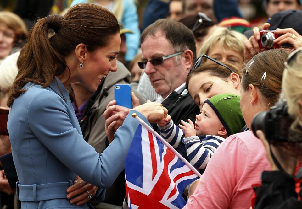 Catherine (L), Duchess of Cambridge, holds the hand of a baby in the crowd after laying a wreath with her husband, Britain's Prince William, at the war memorial in Seymour Square in the town of Blenheim April 10, 2014. The Prince and his wife Kate are undertaking a 19-day official visit to New Zealand and Australia with their son George. REUTERS/Phil Noble (NEW ZEALAND - Tags: ROYALS POLITICS TPX IMAGES OF THE DAY)