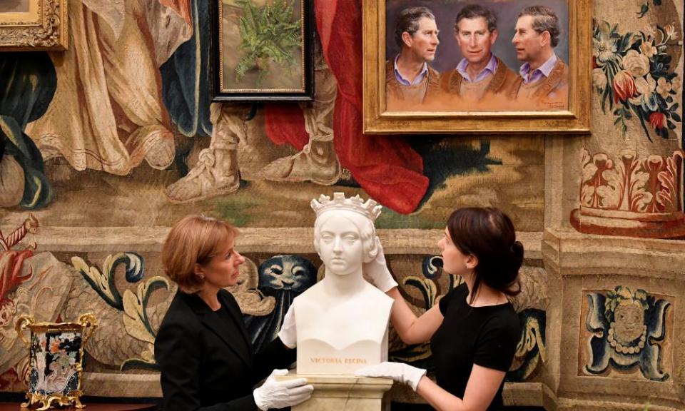 A painting of Prince Charles looks down on curators preparing a marble bust of Queen Victoria for the exhibition.