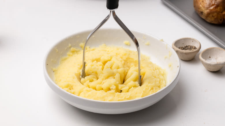 mashing potato in a bowl