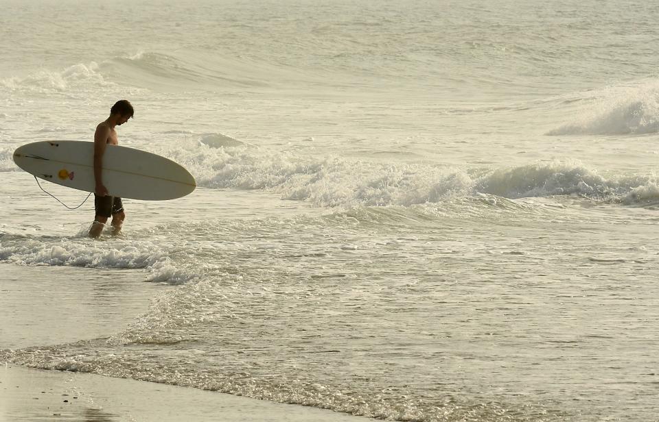 A surfer enters the water on June 14, 2022 at Wrightsville Beach, N.C.