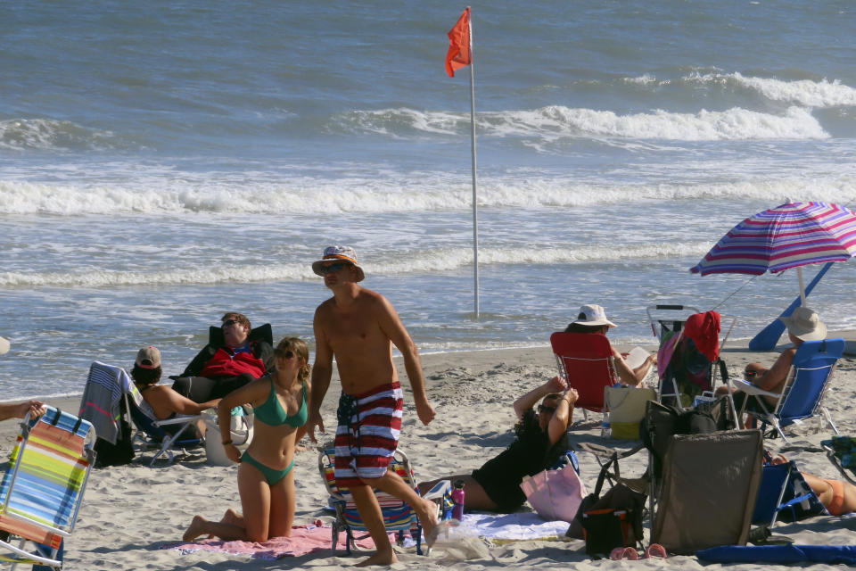 Beachgoers walk on the sand in Brigantine NJ on Aug. 8, 2022. On April 24, 2023, a panel of Democratic federal officials and New Jersey environmental groups said climate change is the biggest threat to marine life in the ocean, not preparatory work for offshore wind farms, which some people believe are harming or killing whales on the East Coast despite government agencies' statements that the two are not related. (AP Photo/Wayne Parry)