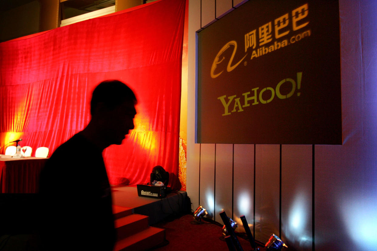In this file photo, a man walks past a sign showing the Yahoo! and Alibaba.com logos. (AP)