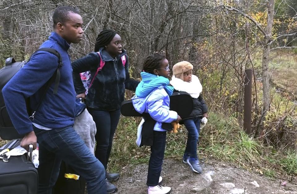In this Nov. 4, 2019, photo, a family from Nigeria waits to illegally cross the U.S. border at Roxham Road in Champlain, N.Y., into Canada where Royal Canadian Mounted Police wait, in Saint-Bernard-de-Lacolle, Quebec. Since early 2017, when people who despaired of finding a permanent safe haven in the United States began turning to Canada for help, around 50,000 people have illegally entered Canada, many through Roxham Road in upstate New York. A case being heard in a Toronto court this week could end the use of Roxham Road. (AP Photo/Wilson Ring)