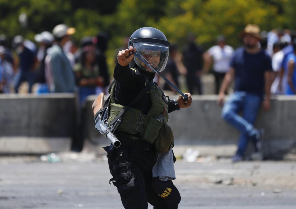 Un policía antimotines utiliza una honda para enfrentarse a seguidores del destituido presidente peruano Pedro Castillo en la autopista Panamericana Norte, en Chao, Perú, el jueves 15 de diciembre de 2022. El nuevo gobierno de Perú declaró 30 días de emergencia nacional el miércoles, en medio de las violentas protestas que sobrevinieron a la destitución de Castillo, que suspenden derechos y libertades públicos en todo el territorio del país andino. (AP Foto/Hugo Curotto)