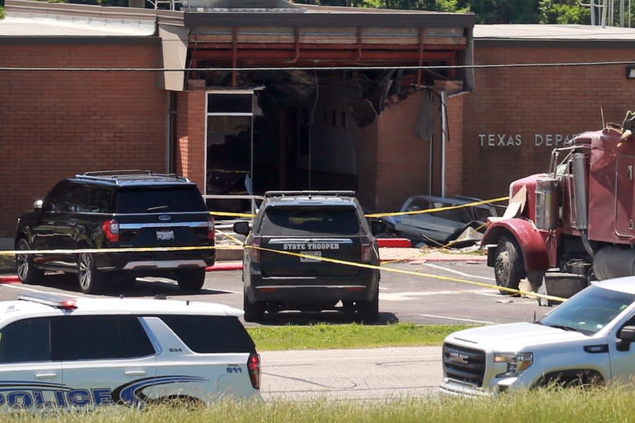 Emergency personnel work at the scene after an 18-wheeler crashed into the Texas Department of Public Safety Office in Brenham, Texas, Friday, April 12, 2024. A suspect is in custody in connection to a commercial vehicle crash at the Texas Department of Public Safety office in the rural town west of Houston. Texas DPS officials say multiple injuries were reported in the crash. (AP Photo/Lekan Oyekanmi)