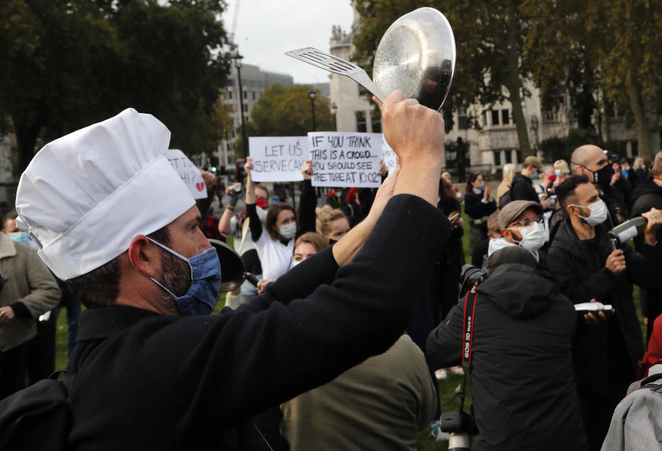 FILE - In this Monday, Oct. 19, 2020 file photo, hospitality workers protest in Parliament Square in London. The coronavirus pandemic is gathering strength again in Europe and, with winter coming, its restaurant industry is struggling. The spring lockdowns were already devastating for many, and now a new set restrictions is dealing a second blow. Some governments have ordered restaurants closed; others have imposed restrictions curtailing how they operate. (AP Photo/Frank Augstein, File)