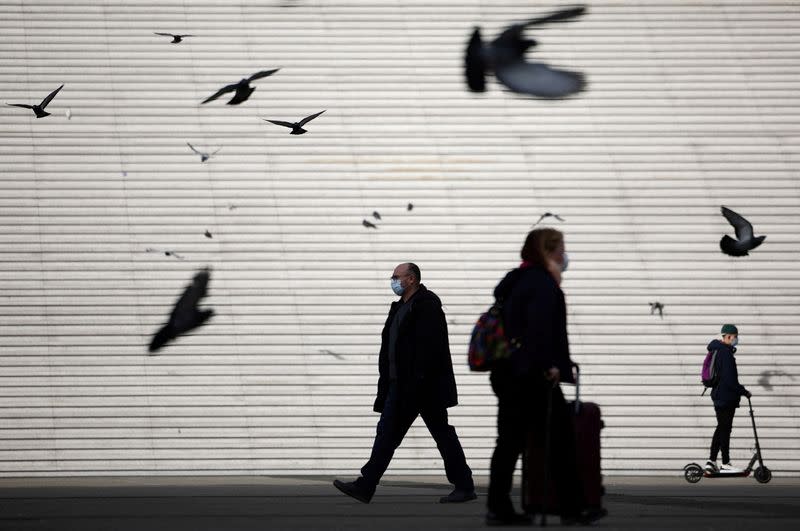 FILE PHOTO: People, wearing protective face masks, walk past the steps near the Grande Arche in La Defense