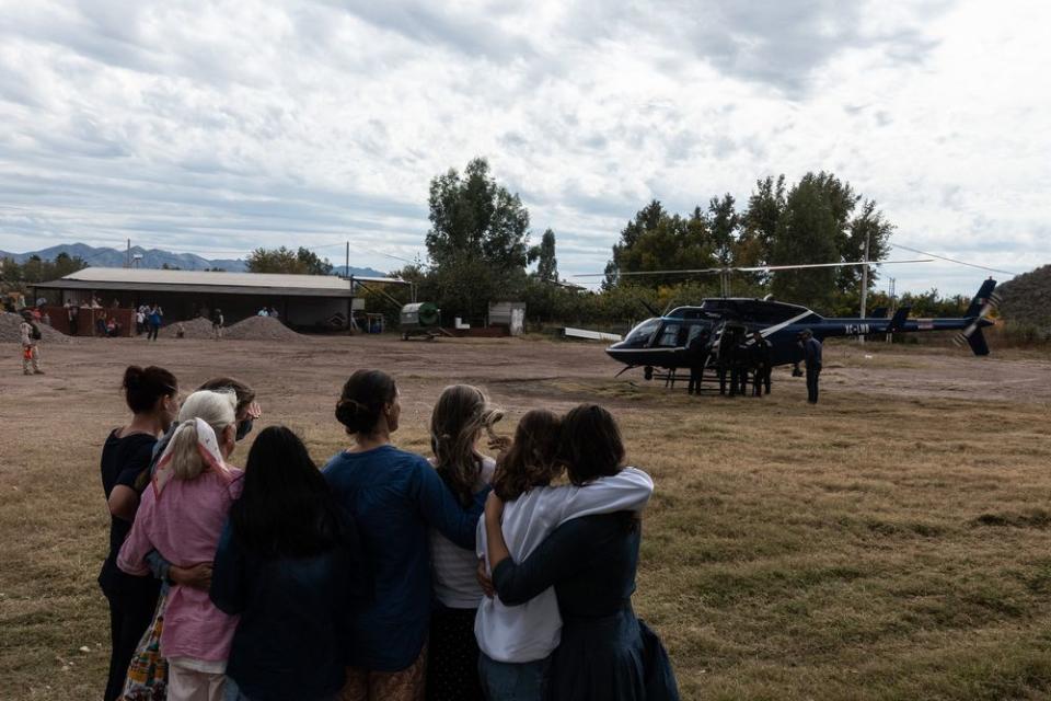 Family members watch a helicopter prepare to leave with the body of Christina Langford Johnson. | César Rodríguez—El País