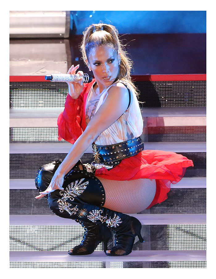 Jennifer Lopez crouches with microphone