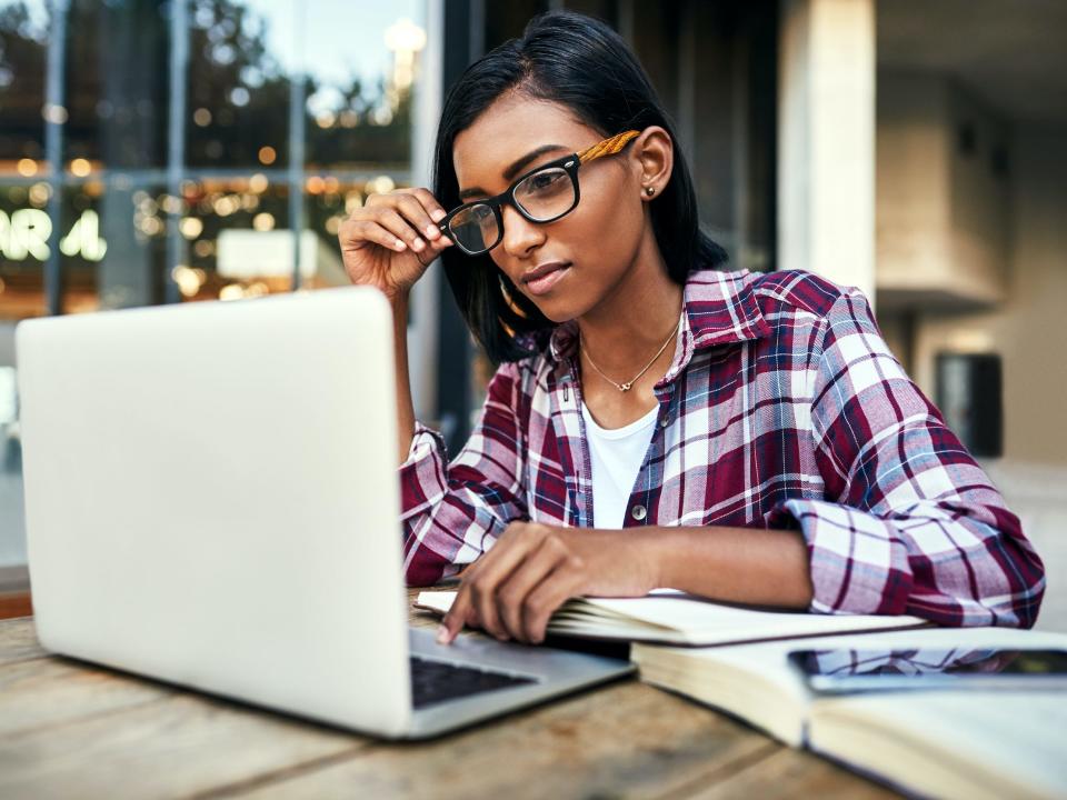 student working on laptop with textbooks