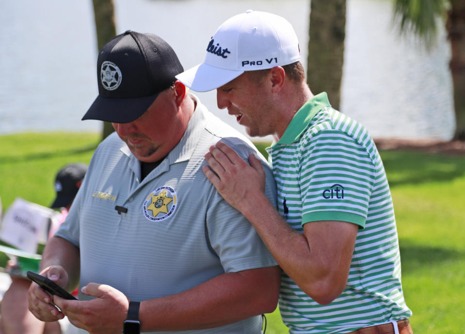 Justin Thomas, right, looks at the phone of Florida Fish and Wildlife Conservation Commission officer John Booth on the third hole during the second round of the Honda Classic golf tournament, Friday, March 1, 2019, in Palm Beach Gardens, Fla. (AP Photo/Wilfredo Lee)