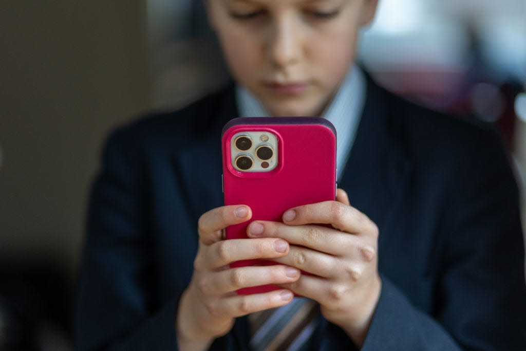 A young boy holding a red cellphone.