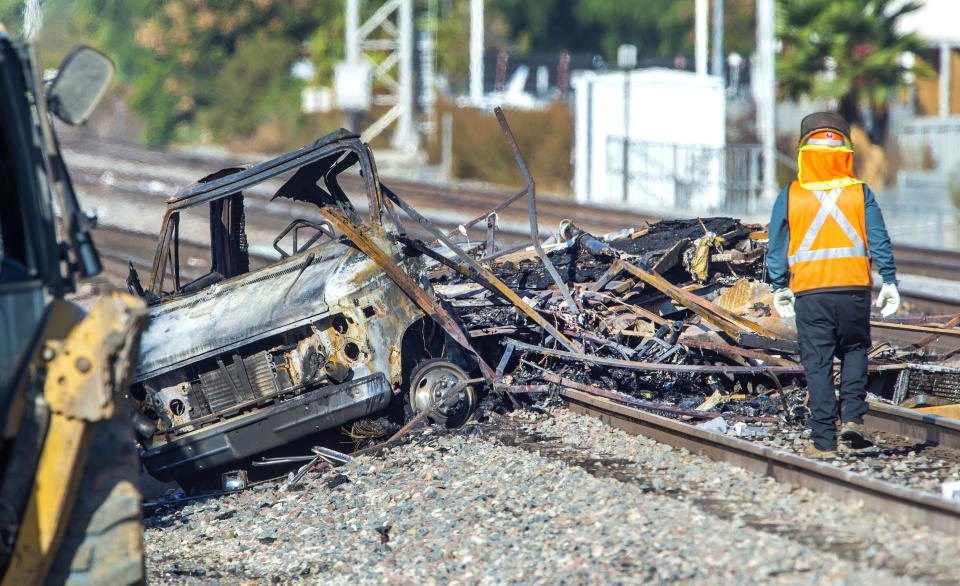 Heavy equipment begins to remove a burned motorhome from the railroad tracks following a collision with a commuter train in Santa Fe Springs, Calif., Friday, Nov. 22, 2019. Authorities say the collision occurred shortly after 5:30 a.m. Friday at an intersection in an industrial area of Santa Fe Springs. There were no immediate reports of injuries. All passengers on the Metrolink train were safely evacuated. (Mark Rightmire/The Orange County Register via AP)
