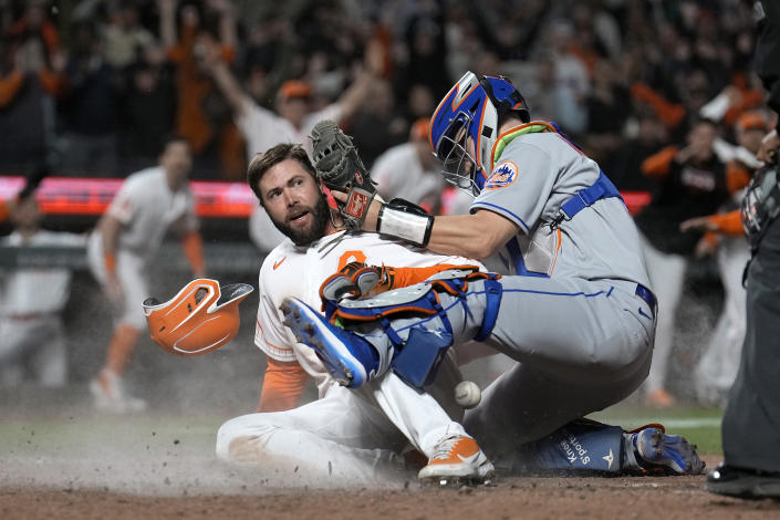 San Francisco Giants' Darin Ruf (33) scores the winning run as New York Mets catcher Tomas Nido, right, drops the ball during the ninth inning of a baseball game in San Francisco, Tuesday, May 24, 2022. The Giants win 13-12. (AP Photo/Tony Avelar)