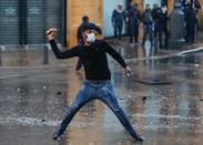 A demonstrator throws a stone during a protest against a ruling elite accused of steering Lebanon towards economic crisis in Beirut