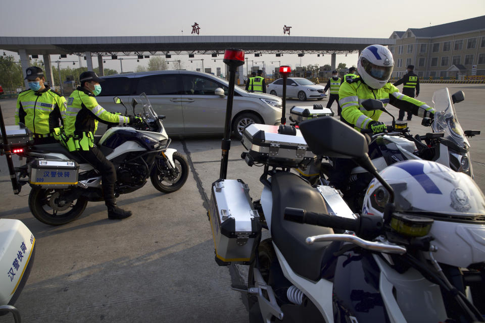 Police officers wearing face masks to protect against the spread of new coronavirus sit on motorcycles near a toll gate for vehicles entering and exiting Wuhan in central China's Hubei Province, Wednesday, April 8, 2020. After 11 weeks of lockdown, the first train departed Wednesday morning from a re-opened Wuhan, the origin point for the coronavirus pandemic, as residents once again were allowed to travel in and out of the sprawling central Chinese city. (AP Photo/Ng Han Guan)