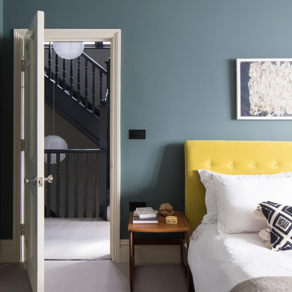 teal painted bedroom with yellow velvet headboard