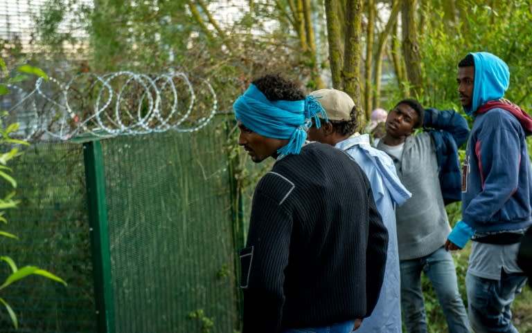 Migrants who managed to get past roadblocks set up by French gendarmes inside the Eurotunnel site, wait near fences topped with barbed wire protecting the boarding platform, in Coquelles near Calais, northern France, on July 31, 2015