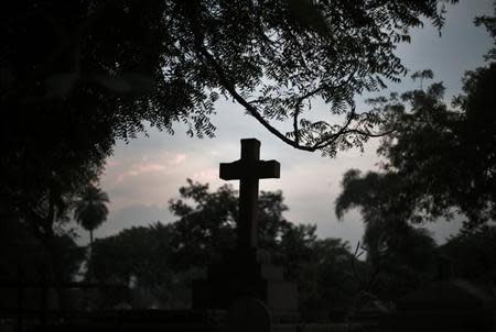 A grave with a cross is seen during sunset at Nicholson Christian Cemetery in old quarters of Delhi February 13, 2014. REUTERS/Adnan Abidi