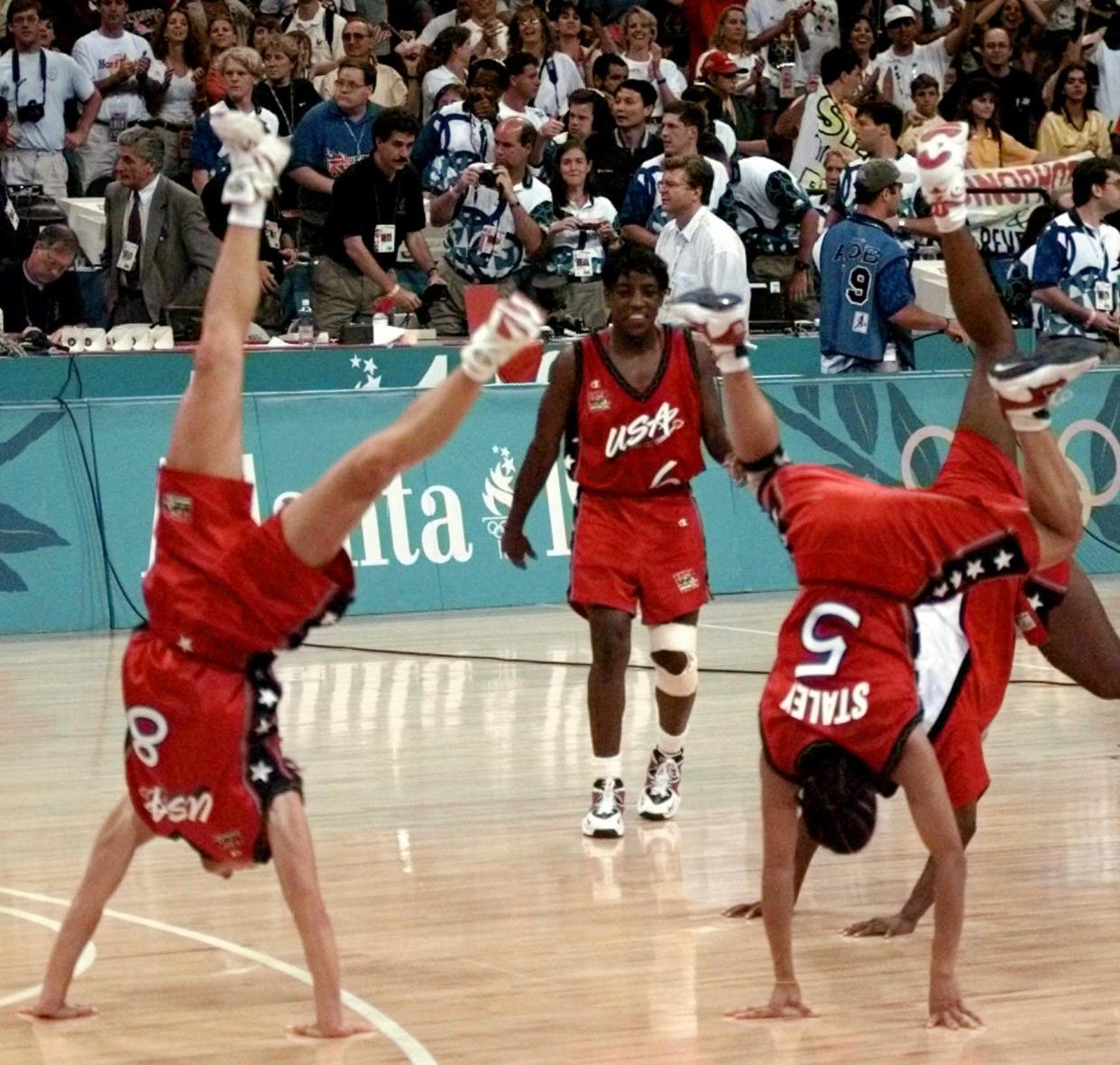 FILE - In this Aug. 4, 1996, file photo, United States team members Jennifer Azzi (8) and Dawn Staley (5) do cartwheels as Ruthie Bolton (6) watches, after the team's victory over Brazil for the gold medal in women's basketball at the Centennial Summer Olympic Games in Atlanta. (AP Photo/John Gaps III, File)