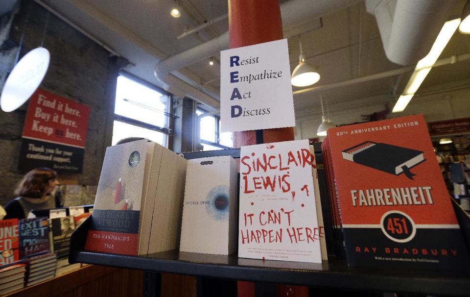 Books are displayed under a sign at the Harvard Book Store, Thursday, March 9, 2017, in Cambridge, Mass. Readers have been flocking to classic works of dystopian fiction in the first months of Donald Trump's presidency. Novels depicting dysfunctional societies have shot to the top of best-seller lists in recent months, including George Orwell's "1984" and Margaret Atwood's "The Handmaid's Tale." Publishers credit Trump's election for sparking demand. (AP Photo/Elise Amendola)