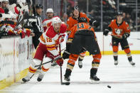 Calgary Flames' Trevor Lewis, left, moves the puck past Anaheim Ducks' Hampus Lindholm during the first period of an NHL hockey game Friday, Dec. 3, 2021, in Anaheim, Calif. (AP Photo/Jae C. Hong)