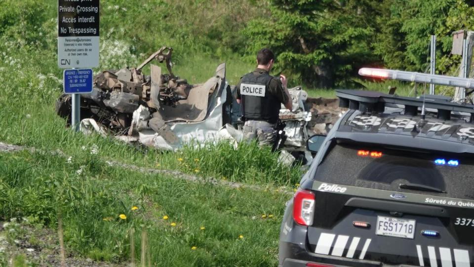 Police inspect the remains of a white van after a collision with a Via Rail train in Coteau-du-Lac, in Montérégie.  (François Sauvé/Radio-Canada - image credit)