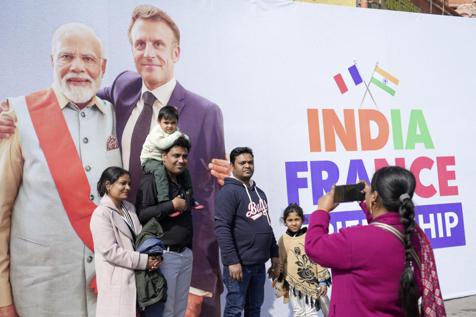 An Indian family gets themselves photographed infant of a billboard showing French President Emmanuel Macron with Indian Prime Minister Narendra Modi erected ahead of Macron's arrival in Jaipur, Rajasthan, India, Thursday, Jan.25, 2024. Macron will be the chief guest at India's annual republic day parade in New Delhi on Friday. (AP Photo/Deepak Sharma)