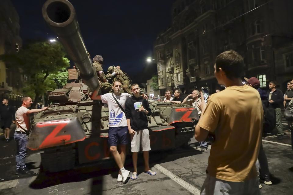 FILE - Servicemen of the Wagner Group military company sit atop of a tank, as local civilians pose for a photo prior to their leave an area at the HQ of the Southern Military District in a street in Rostov-on-Don, Russia, June 24, 2023. Prigozhin's uprising marked the most serious challenge to Russian President Vladimir Putin's rule in his more than two decades in power and badly dented his authority. President Vladimir Putin is likely to win another six-year term easily in an election expected in March, using his sweeping grip on Russia’s political scene to extend his tenure of over two decades in power. (AP Photo, File)