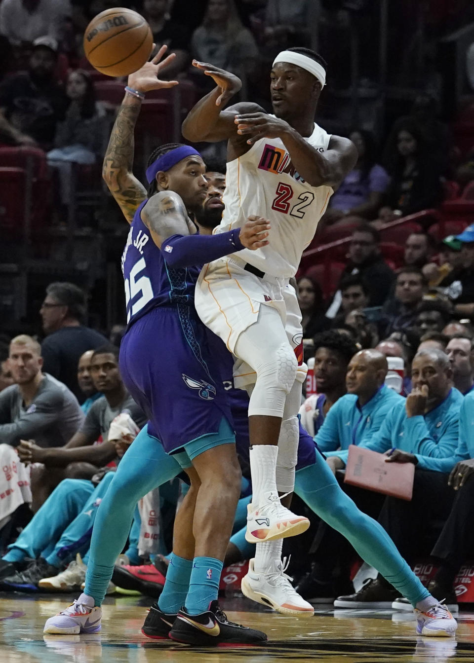 Miami Heat forward Jimmy Butler (22) passes the ball under pressure from Charlotte Hornets forward P.J. Washington (25) during the first half of an NBA basketball game Thursday, Nov. 10, 2022, in Miami. (AP Photo/Marta Lavandier)