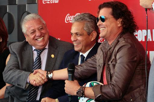 El cantante y compositos colombiano Carlos Vives (D) estrecha la mano al presidente de la Federación Ecautoriana de Fútbol (I) Luis Chiriboga frente al seleccionado de Ecuador, el colombiano Reinaldo Rueda, el 25 de enero de 2014 en Quito. (AFP/Archivos | Juan Cevallos)