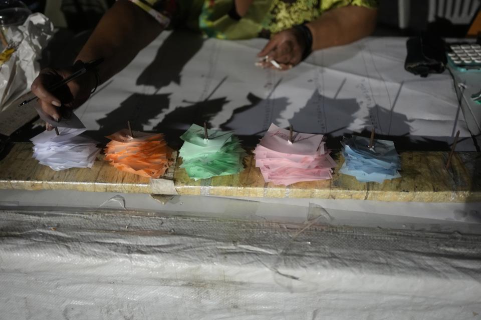 A woman uses small papers to keep participants' bills of a festivity, known as Panigiri, in Aski village about 115 kilometers (72 miles) north of Athens, Greece, early Sunday, Aug. 14, 2022. The Dormition of the Virgin Mary (or Mother of God as the Greeks usually refer to her) is celebrated on Aug. 15. The religious event is coupled with midsummer festivities, known as Panigiria, that often last more than a day with music, culinary feasts and, in many cases, flea markets. (AP Photo/Thanassis Stavrakis)