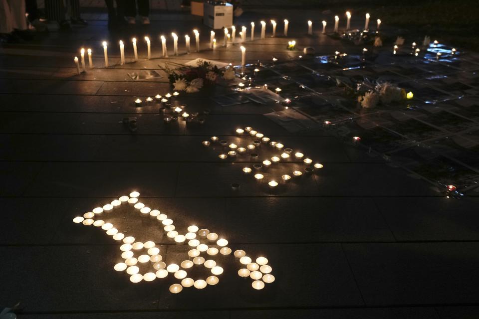 University students light candles to form a "Goddess of Democracy," front, at the site after the "Goddess of Democracy" statue, a memorial for those killed in the 1989 Tiananmen crackdown, was removed from the Chinese University of Hong Kong, Friday, Dec. 24, 2021. The university early Friday morning took down the statue that was based on a figure created by art students and brought to the square shortly before the crackdown in which hundreds of people were killed. (AP Photo/Vincent Yu)