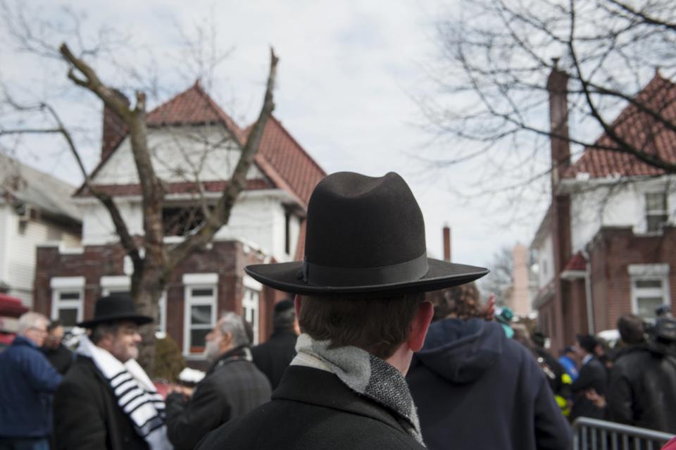 Community members stand at the site of a home fire in the Midwood neighborhood of Brooklyn, New York