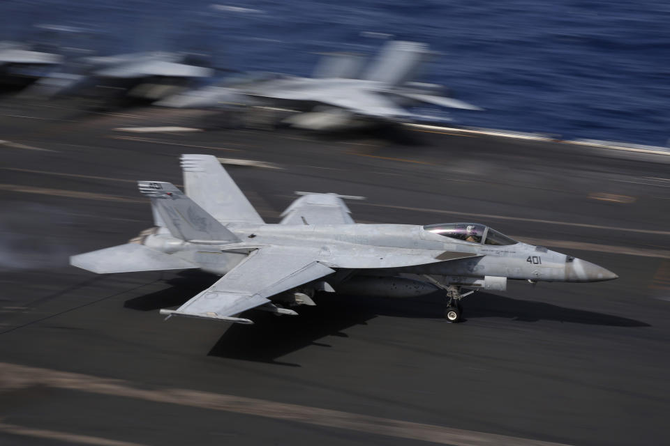 In this Nov. 20, 2018, photo, an F/A-18 Super Hornet fighter jet lands on the deck of the U.S. Navy USS Ronald Reagan in the South China Sea. China is allowing a U.S. Navy aircraft carrier and its battle group to make a port call in Hong Kong after it turned down similar request amid tensions with Washington. (AP Photo/Kin Cheung, File)