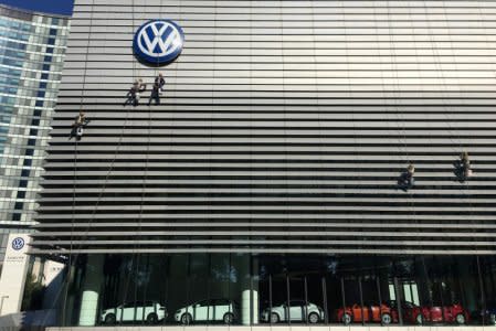 Workers clean the facade of a car showroom under a Volkswagen logo on the Chinese National Day in Beijing, China October 1, 2018. Picture taken October 1, 2018. REUTERS/Stringer