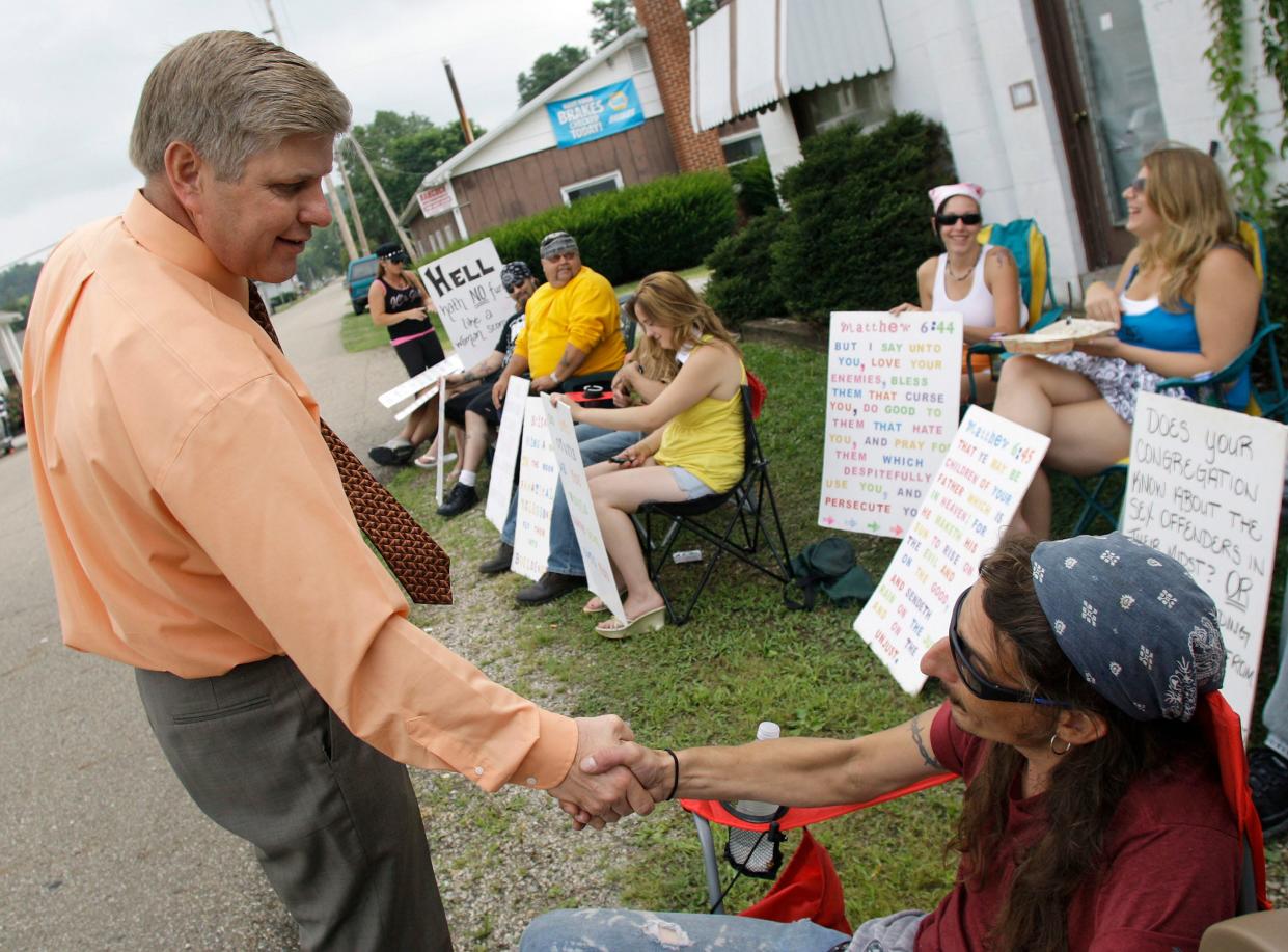 Pastor Bill Dunfee greets protesters outside his church in Warsaw, Ohio, on Sunday, Aug. 22, 2010.