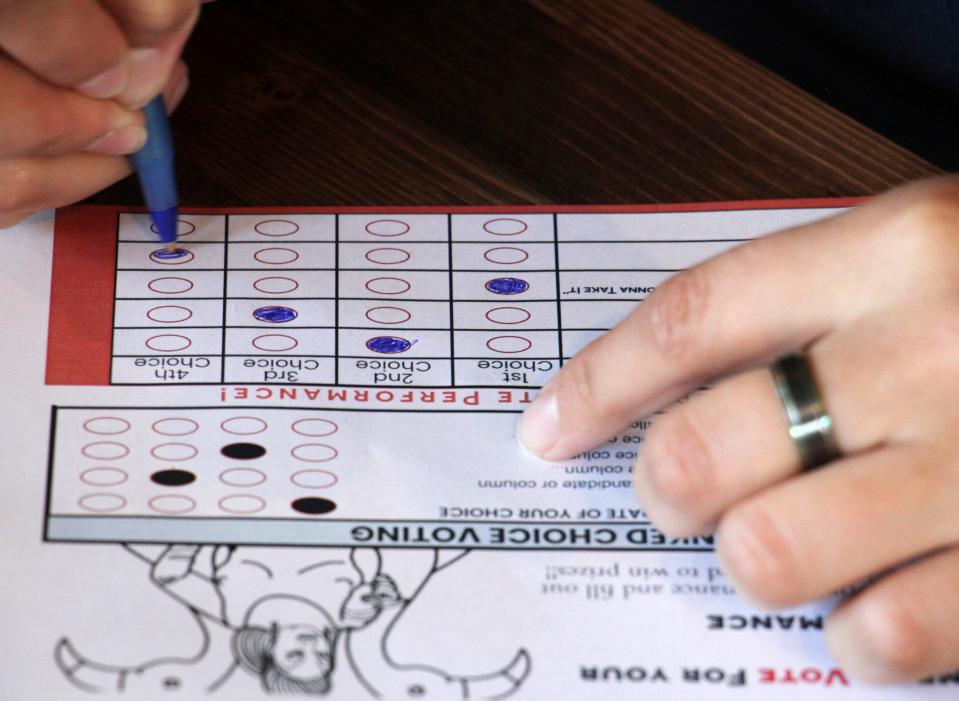 A person completes a ballot in a mock election at Cafecito Bonito in Anchorage, Alaska, in summer 2022, where people ranked the performances by drag performers.