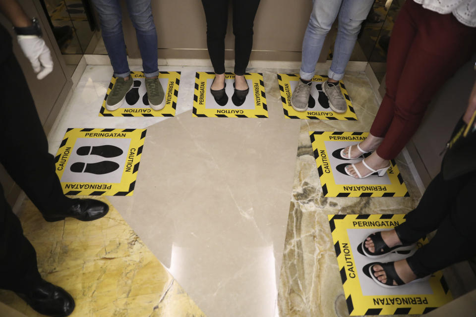 People stand in designated areas on the floor of an elevator as a social distancing effort to prevent the spread of the new coronavirus at a shopping mall in Surabaya, Indonesia, Thursday, March 19, 2020. The vast majority of people recover from the new coronavirus. According to the World Health Organization, most people recover in about two to six weeks, depending on the severity of the illness. (AP Photo/Trisnadi)
