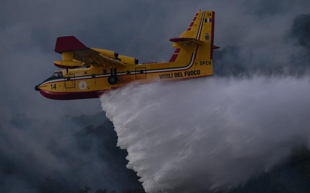 ORISTANO, ITALY - JULY 25: A tanker plane drops water on a blaze that has destroyed thousands of hectares of land - Emanuele Perrone/Getty