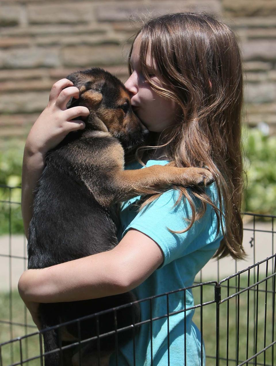 Isabel Buck, 9, gives a smooch to one of thepuppies of her dog Crystal, at her home in New Franklin. The puppies, five females and five males, will be available for adoption through Paws and Prayers Rescue.