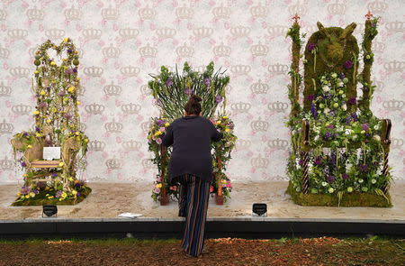 A woman makes adjustments to a floral display based on thrones and chairs at the RHS Chelsea Flower Show in London, Britain, May 21, 2018. REUTERS/Toby Melville