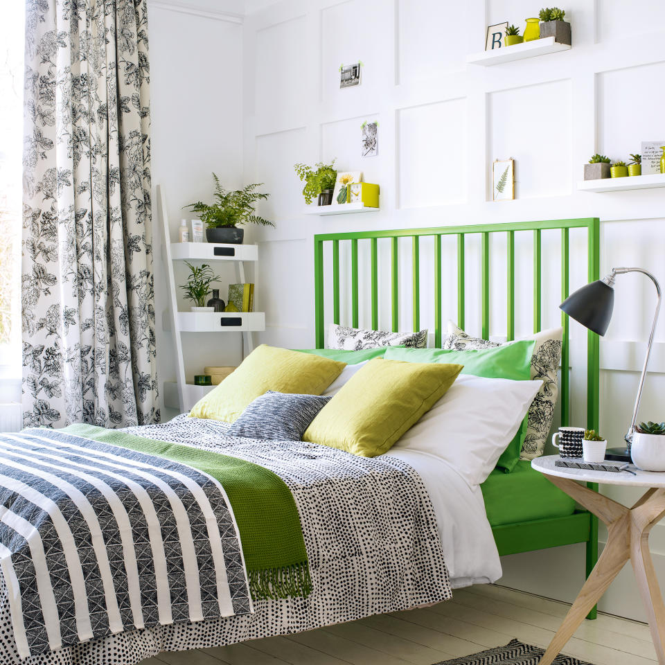 White bedroom with green bed, wall panelling and black details