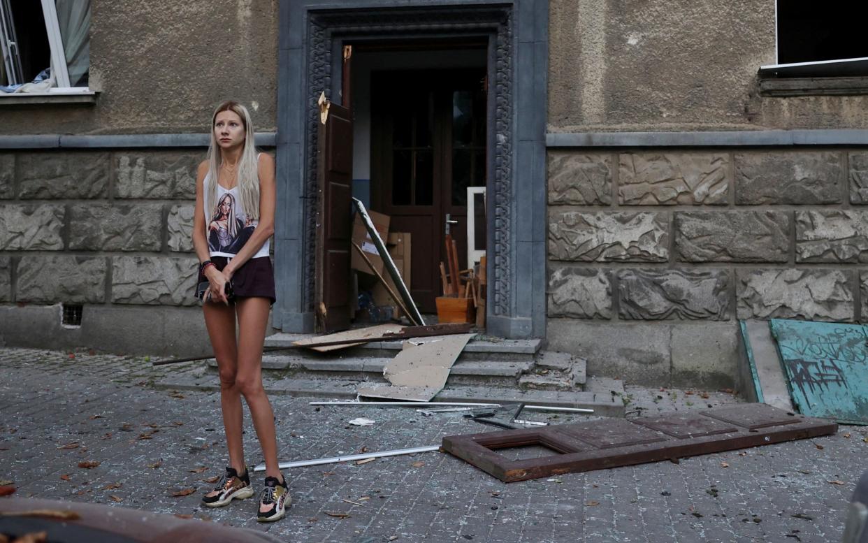 A woman stands in front of a residental building damaged during the Russian strike in Lviv